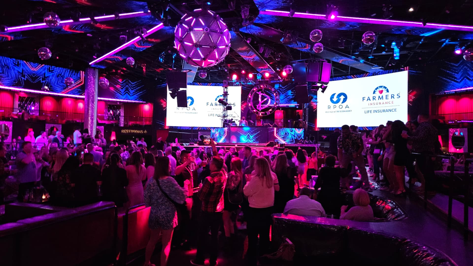 Guests gathered beneath purple lighting at a Farmers celebration